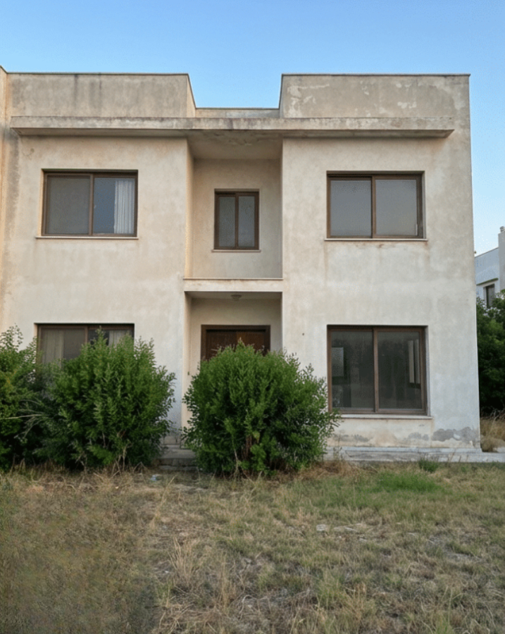 Villa before renovation: bare render, dated windows and an overgrown plot
