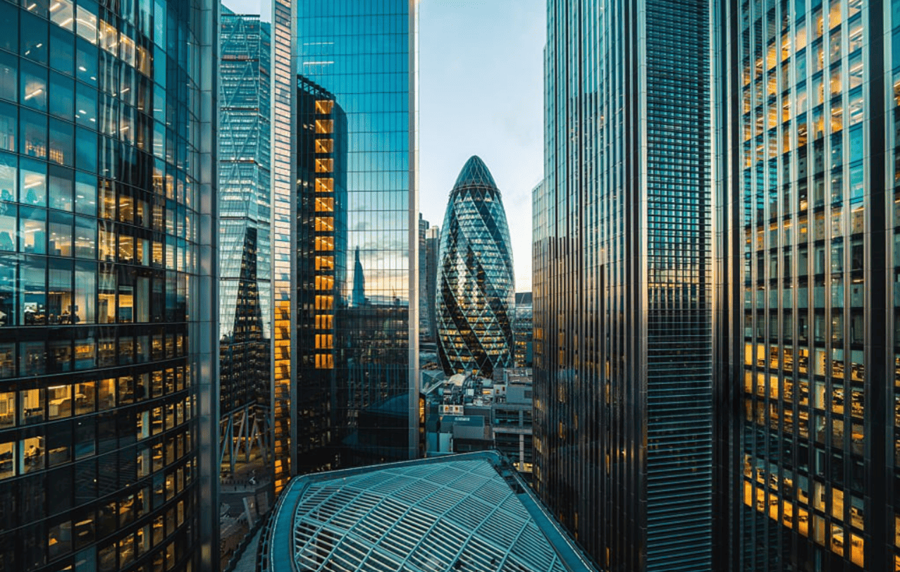 Glass office towers lit from within at dusk across a city financial district