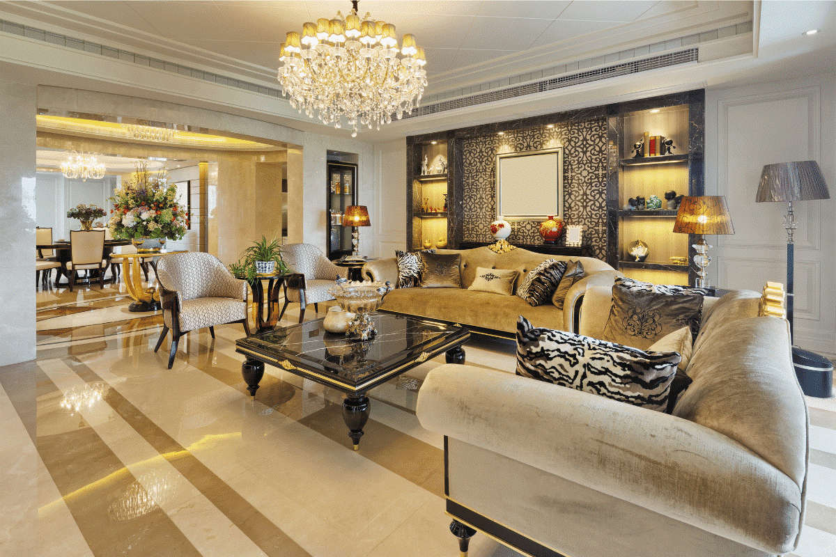Villa living room with a crystal chandelier, marble floors, lit stone niches and gold toned upholstery